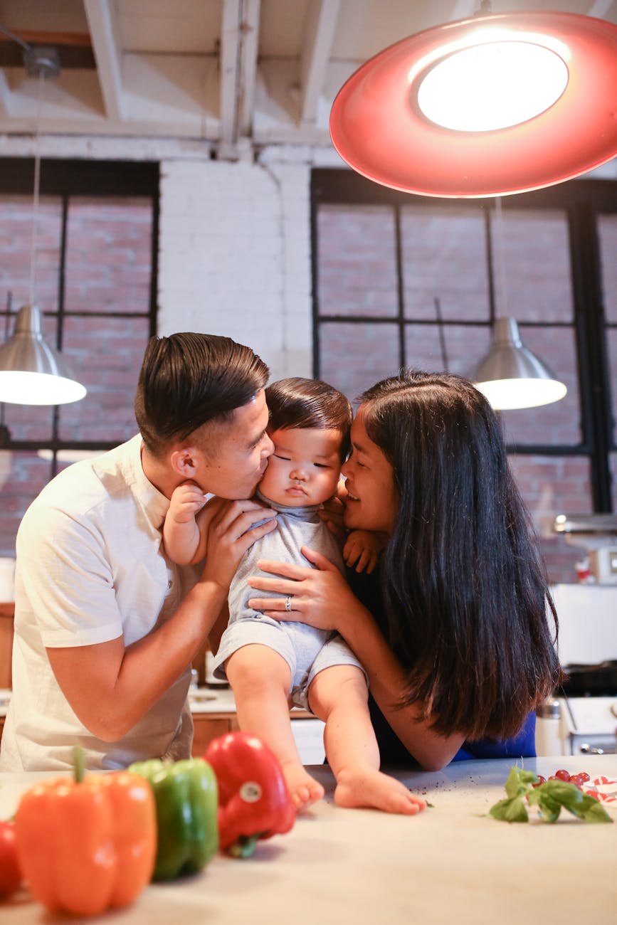 man and woman hugging baby in blue onesie